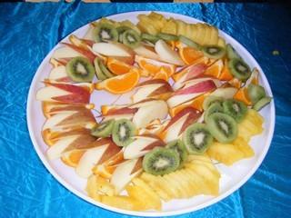 皿に盛られたキウイ、オレンジ、リンゴ等のカットフルーツの写真