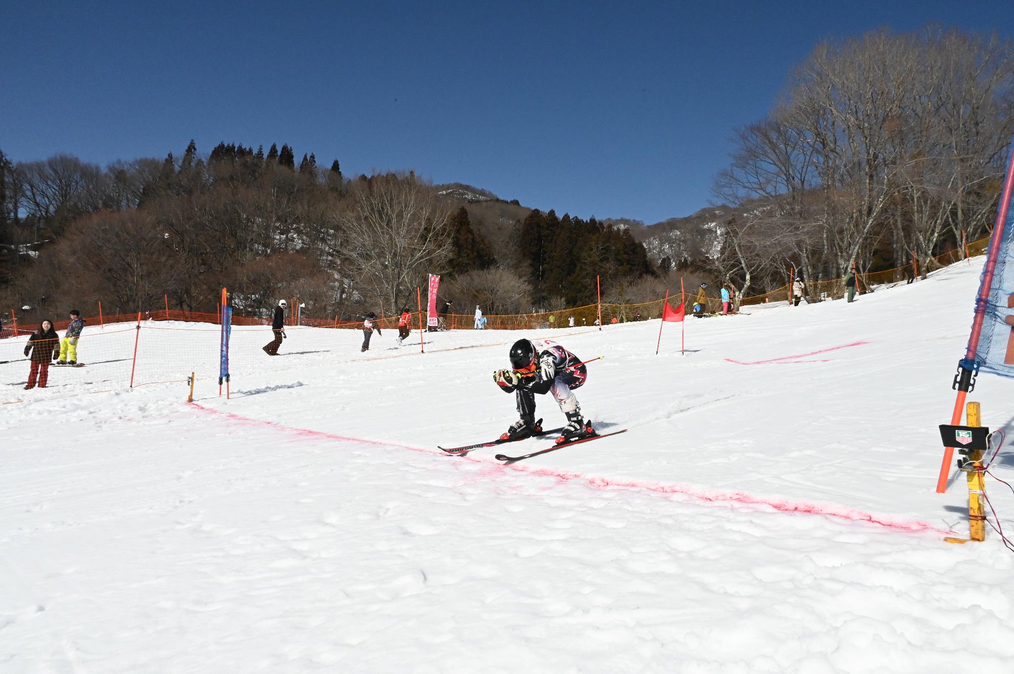 スキーで滑っておりゴールを切った参加者の写真