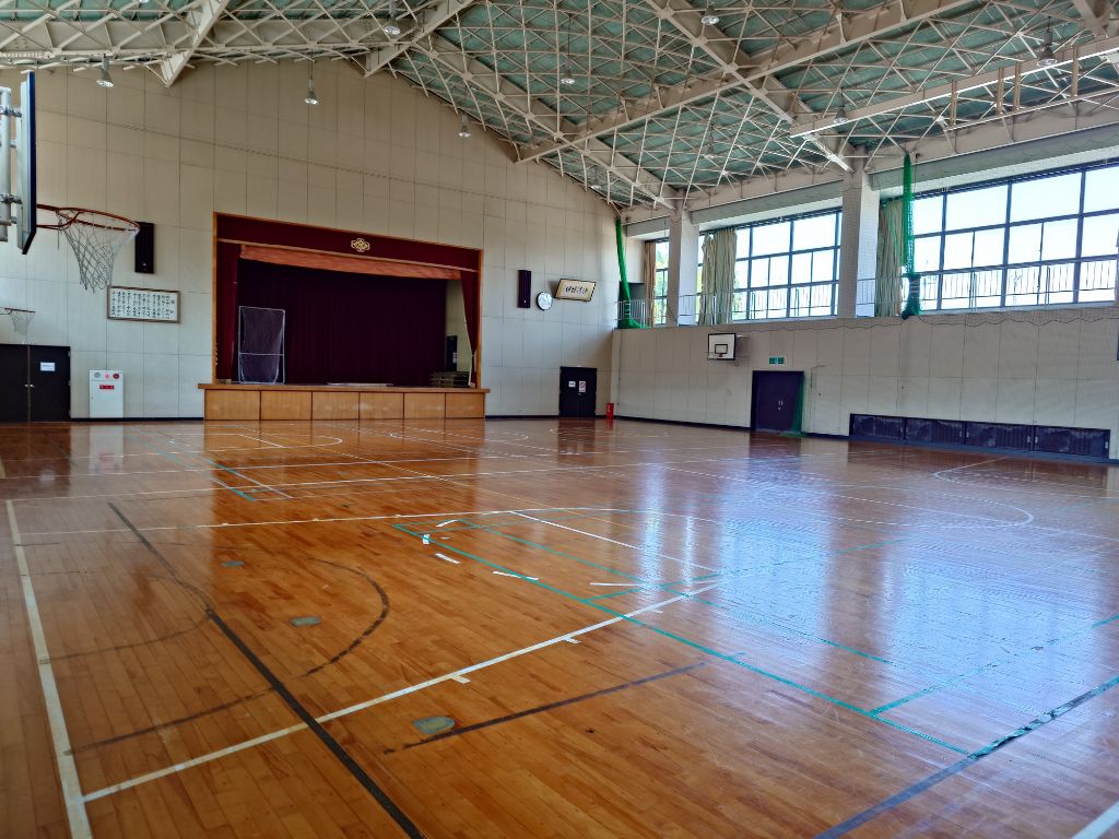 息郷体育館の屋内の写真。手前にバスケットボールのリングがある