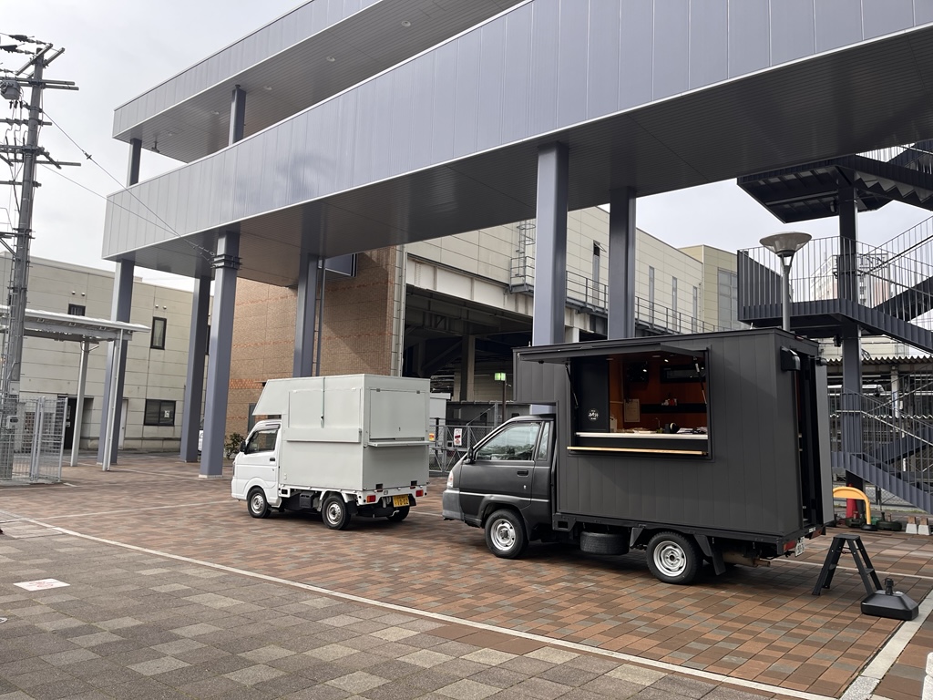 連絡通路下にあるキッチンカー2台の写真。